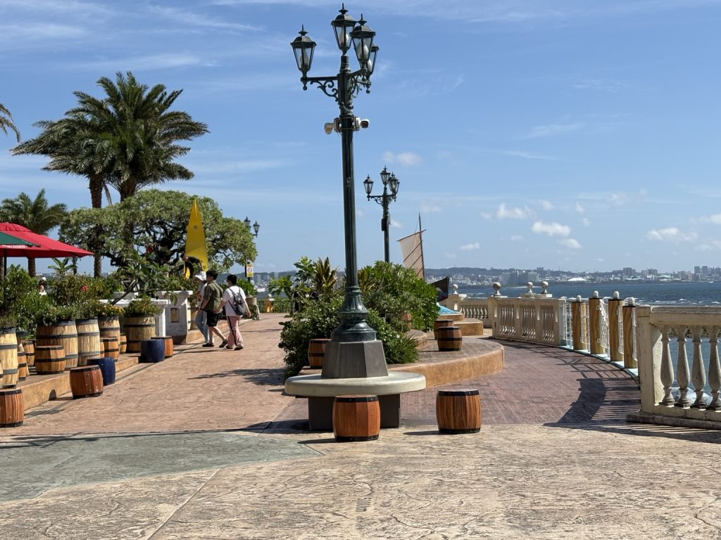 デポアイランドの海沿い遊歩道と街灯、ヤシの木、海を望む景色