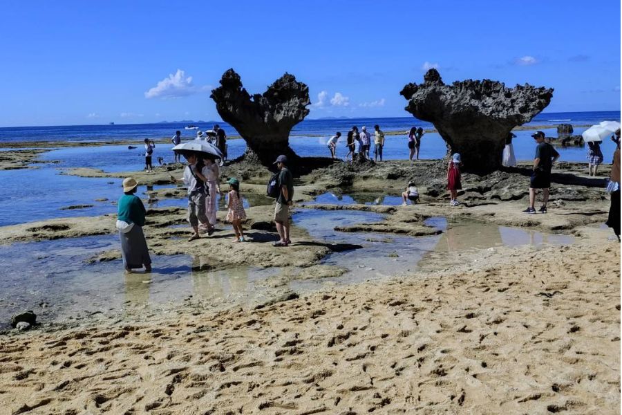 干潮時の古宇利島・ハートロック周辺。潮だまりや岩場を散策する観光客でにぎわう様子。